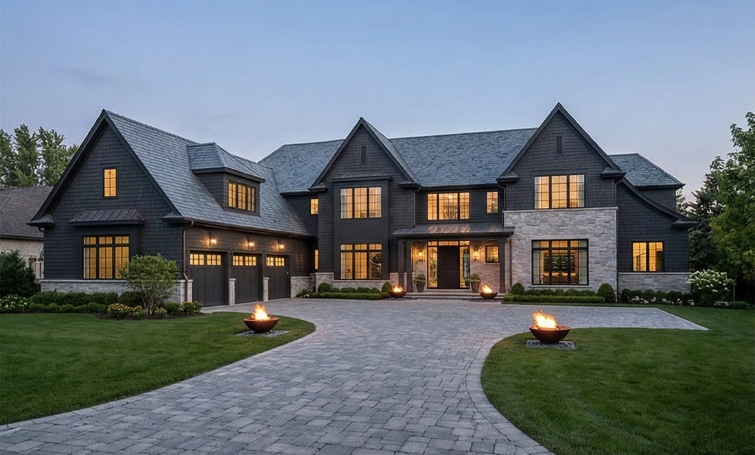Dark-shingle luxury residence at dusk with fire bowls
